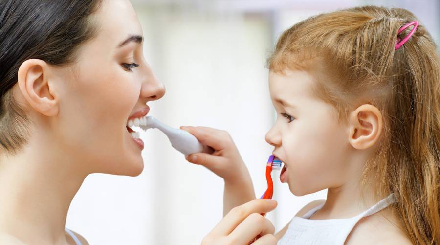 Parent brushing a toddler’s teeth using the correct technique for effective oral hygiene.